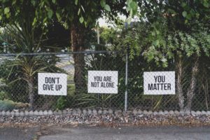 Chain link fence containing three signs that read: "Don't give up," "You Are Not Alone" and "You Matter"