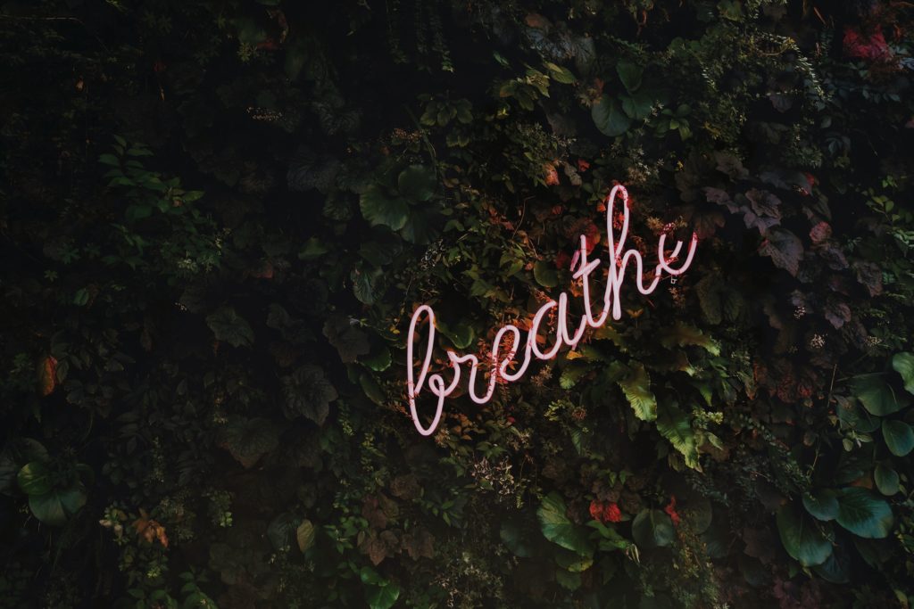 Image of dark rocks with the word "breathe" in cursive writing.